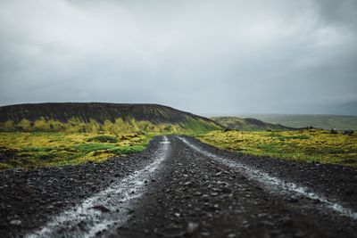 Road amidst green landscape against sky