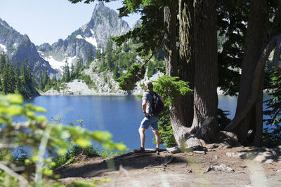 Man by tree by lake against mountain
