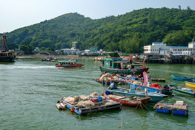 Boats moored on river by tree mountains against clear sky
