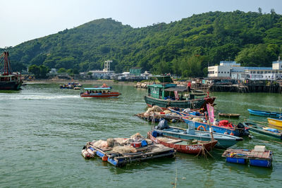 Boats moored on chinese river by tree mountains against clear sky