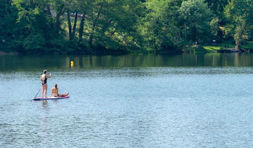 Women paddleboarding in lake against trees