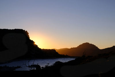 Scenic view of silhouette mountains against clear sky during sunset