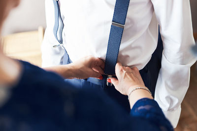 Midsection of mother adjusting suspenders on son during wedding ceremony