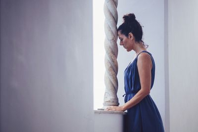 Side view of woman standing by column