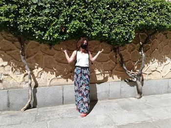 Full length of woman standing against wall