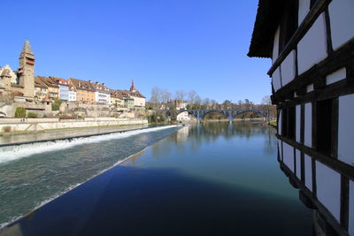 Canal amidst buildings against clear blue sky