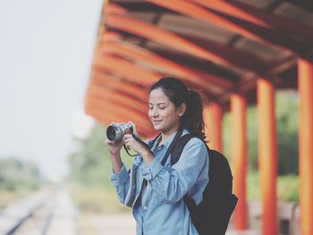 Young woman photographing while standing outdoors