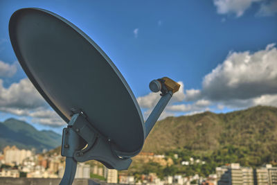 Satellite antenna with city and blue sky background, selective focus