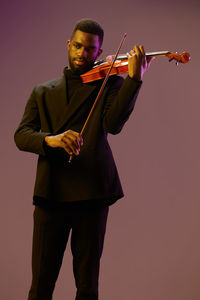 Man holding violin while standing against white background