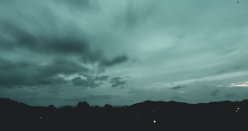 Silhouette of trees against cloudy sky