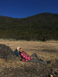 Man lying down on land against sky