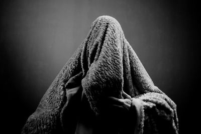 Man wrapped in blanket against wall