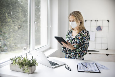 Woman holding smart phone while standing on table