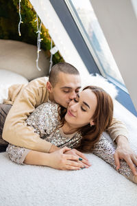 Portrait of smiling young woman lying on bed at home