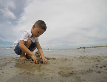 Full length of boy on beach against sky