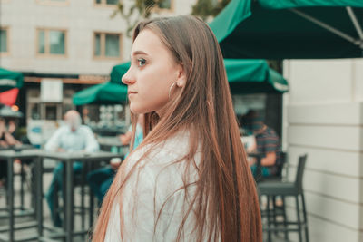Close-up of young woman standing by sidewalk cafe