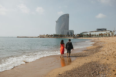 Rear view of people on beach against sky