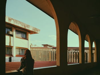 Rear view of woman standing against buildings in city