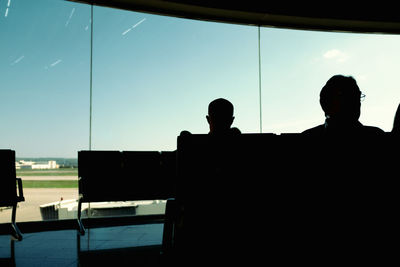 Rear view of silhouette man sitting on glass window