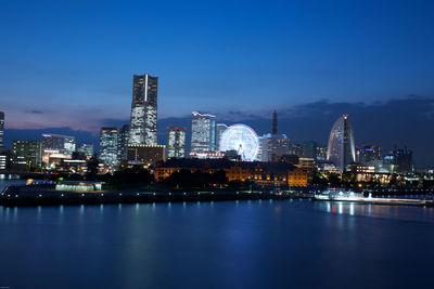 Illuminated cityscape against blue sky