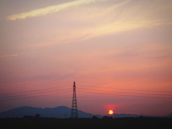 Silhouette electricity pylons against sky during sunset