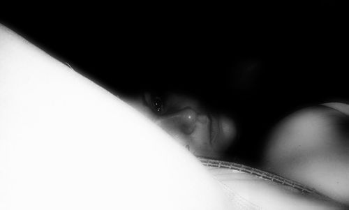Close-up portrait of woman lying down on black background