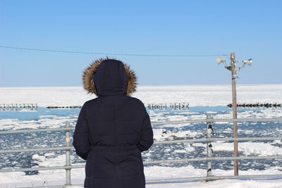 Rear view of woman standing against frozen sea
