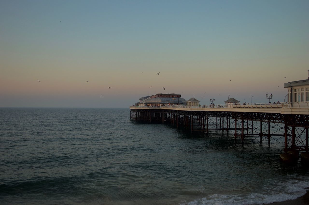 sea, horizon over water, water, pier, built structure, scenics, dusk, architecture, tranquility, clear sky, tranquil scene, flying, waterfront, beauty in nature, nature, sky, outdoors, jetty, shore, no people, seascape, man made structure