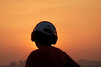 Rear view of man standing against orange sky