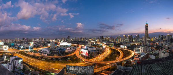 High angle view of city lit up against cloudy sky
