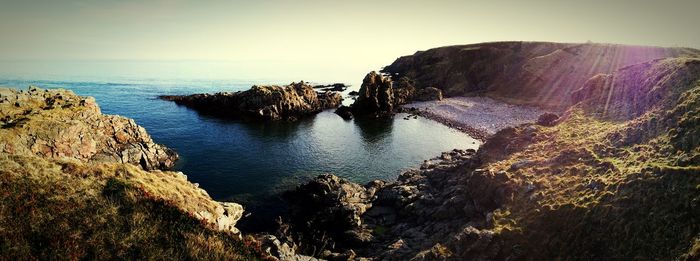 Rock formations by sea against clear sky