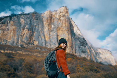 Full length of woman standing on rock against sky