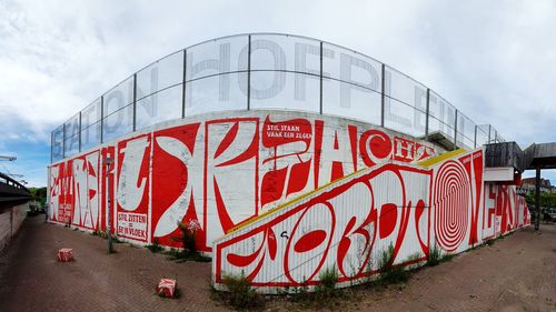 Graffiti on wall by road against sky