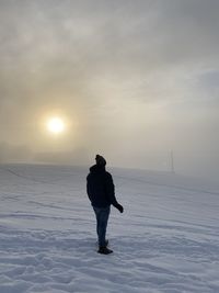 Rear view of man standing on snow covered field