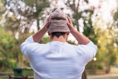 Rear view of man wearing hat standing against trees