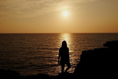 Silhouette people standing on beach during sunset