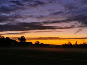 Scenic view of silhouette field against sky at sunset