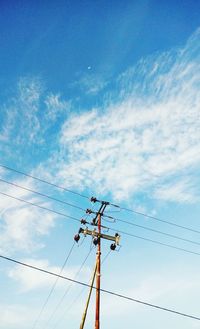 Low angle view of electricity pylon against blue sky