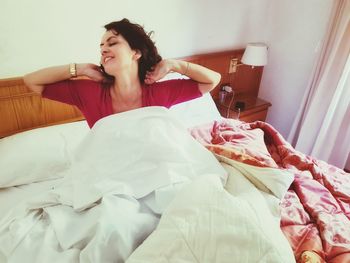 Young woman sitting on bed at home