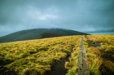 Scenic view of grassy field against cloudy sky