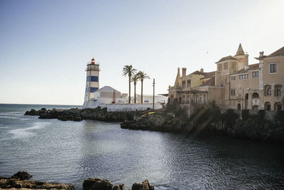 Buildings by sea against clear sky