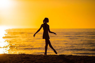 Silhouette woman standing at beach during sunset