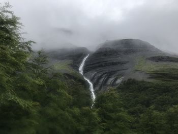 Scenic view of waterfall in forest against sky