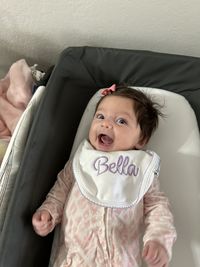 High angle view of cute baby girl sitting on bed at home