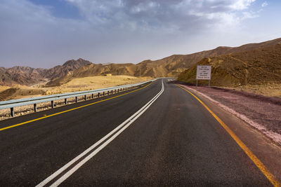 Road leading towards mountains against sky