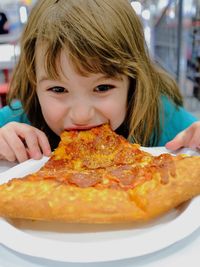 Close-up portrait of girl eating pizza in restaurant