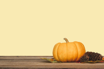 Pumpkins on wooden table against orange background