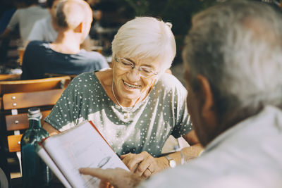 Senior couple tourist discussing menu while sitting at restaurant in city