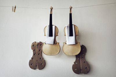 Incomplete violins hanging on string against wall