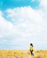 Side view of woman running on field against sky